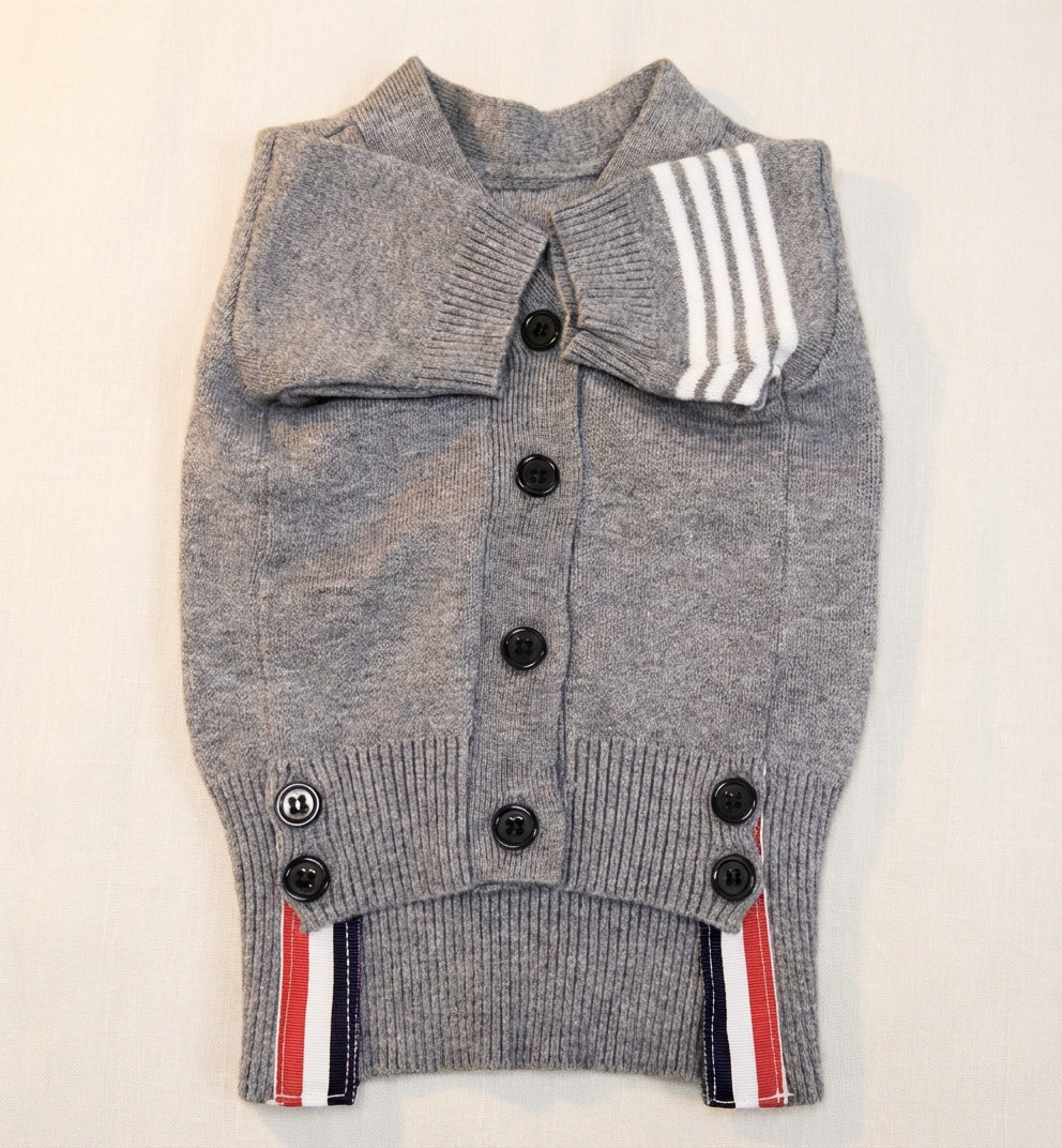 グレーのニットカーディガン（PetoPop製）、クラシックなトリコロールストライプと黒いボタンが特徴
