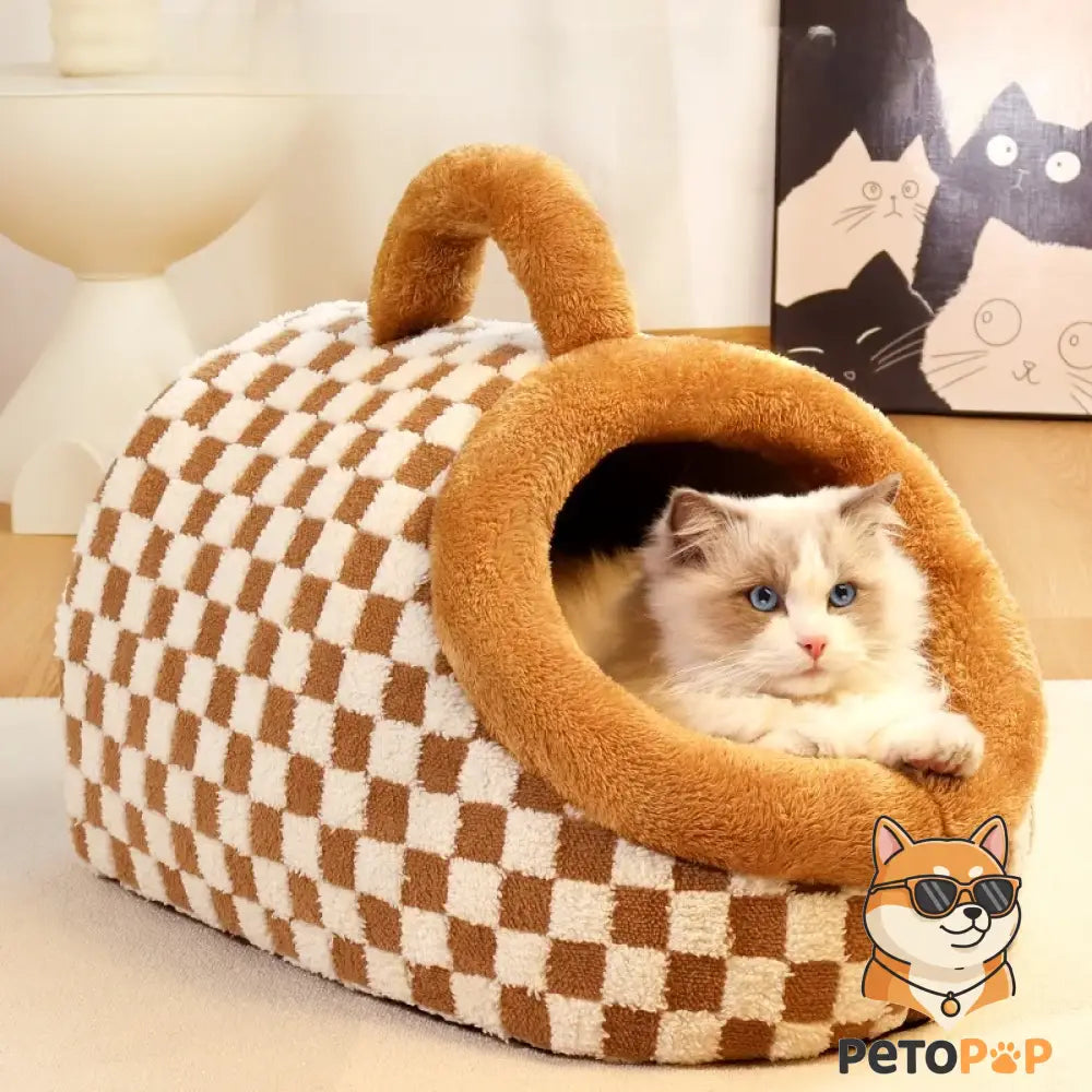 茶色のチェック柄のテント型ペットハウス（PetoPop製）で、中には青い目の猫が横たわっています。